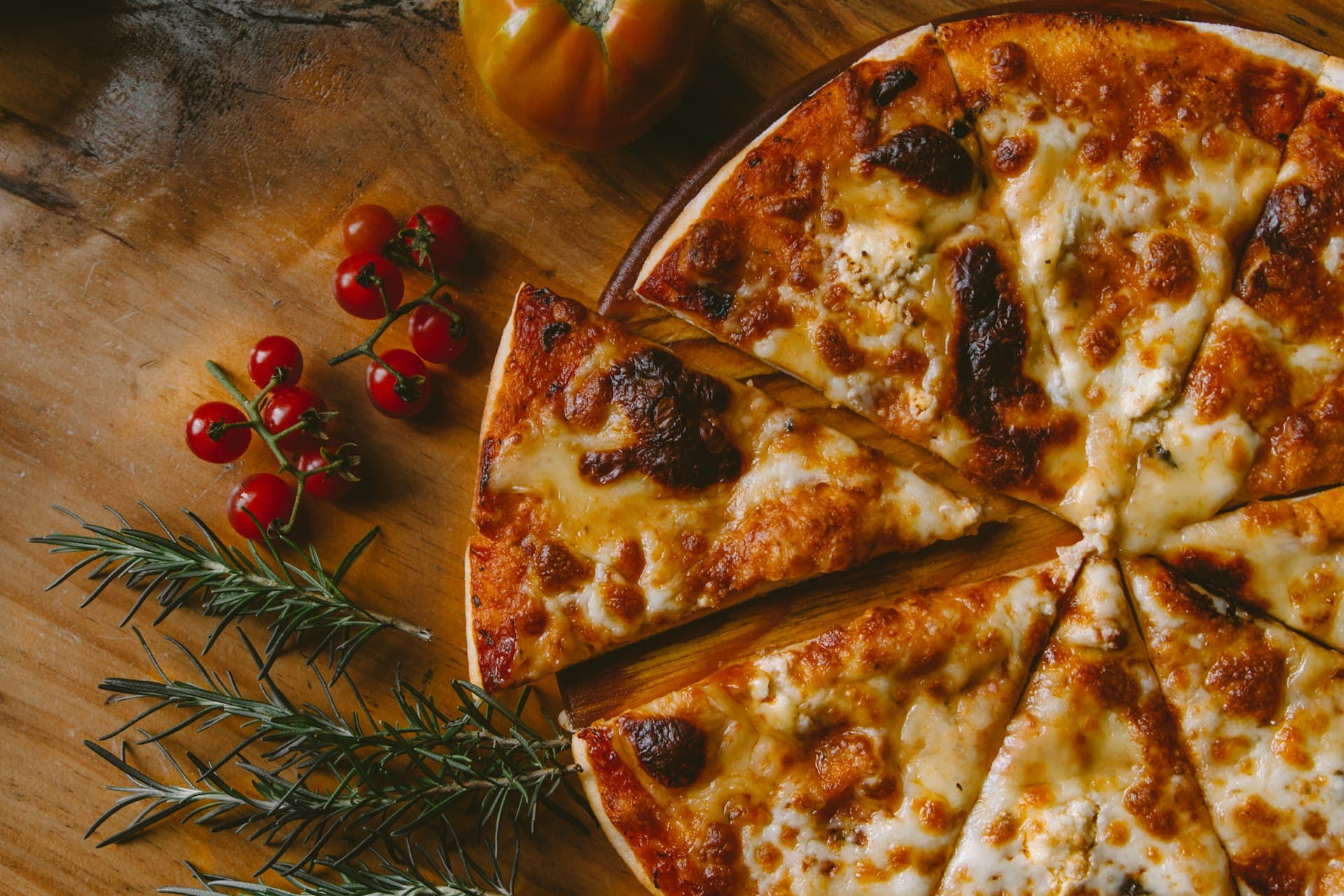 Pizzabakker schuift een pizza in een brandende houtoven in de donkere keuken van Pizzeria Mafia