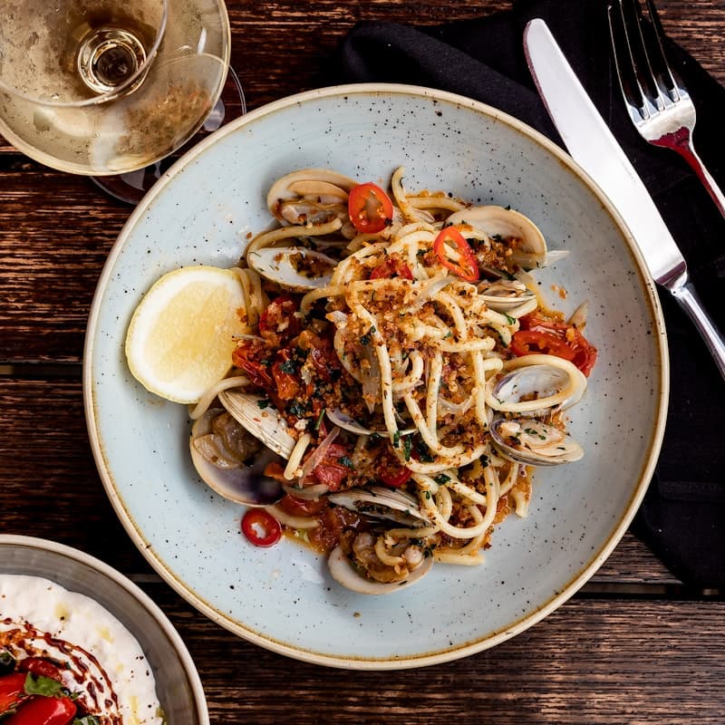 Drie krokant gefrituurde rijstballen op een donker bord met rode tomatendip